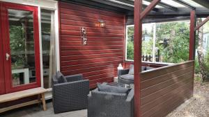 une terrasse couverte avec des chaises en osier sur une maison dans l'établissement Bosbungalow de Eekhoorn, à Nunspeet