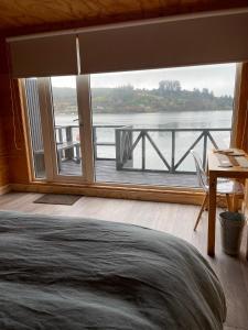 a bedroom with a large window with a view of the water at Hotel Palafito Entre Mar y Tierra in Castro