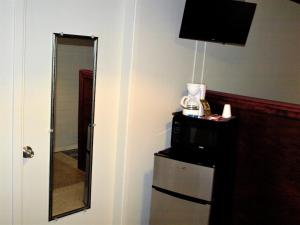 um quarto com um espelho, uma televisão e um frigorífico em Auberge Internationale La Vieille École em Sainte-Anne-des-Monts