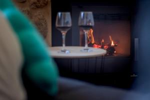 two wine glasses sitting on a table in front of a fireplace at Tía Amalia - Con vistas al mar in Carnota