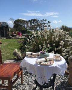 a table with a white table cloth and a vase on it at Castaway East - Long Island in Schull