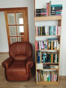 una silla de cuero marrón junto a una estantería con libros en Alto Santiago, en San Vicente de la Barquera