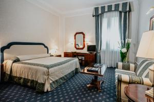 Pokój hotelowy z łóżkiem i lustrem w obiekcie Hotel De La Ville we Florencji +37 zdjęć