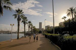 un homme et une femme marchant sur un trottoir avec un enfant dans l'établissement Apartamentos Santa Barbara, à Alicante