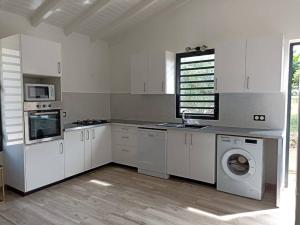 a kitchen with white cabinets and a washer and dryer at Villa Catalina in Le Moule