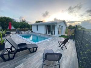 a deck with a pool and chairs and a house at Villa Catalina in Le Moule