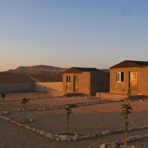 a group of buildings in a desert with trees at Dana Sunset Eco Camp in Dana