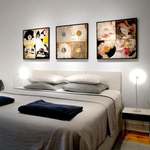 a bedroom with a bed with four pictures on the wall at New Art Apartment in Lisbon
