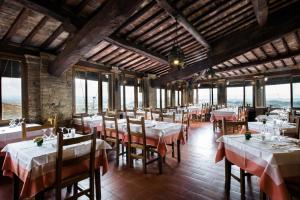 un restaurante con mesas y sillas en una sala con ventanas en Hotel La Cisterna, en San Gimignano