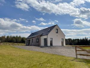 a white barn with a black roof on a field at Eagle Landing in Culbokie