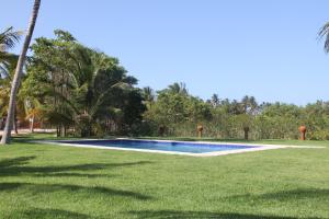 a swimming pool in the middle of a grass field at Pousada Wind Rose in Itarema