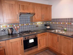 a kitchen with wooden cabinets and a sink at Hewlett Apartments in Cheltenham