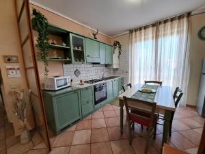 バーニ・サン・フィリッポにあるApartament Thermaeのキッチン(緑のキャビネット、テーブル、椅子付)