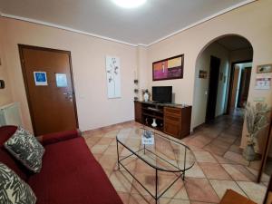 sala de estar con sofá rojo y mesa de cristal en Apartament Thermae en Bagni San Filippo