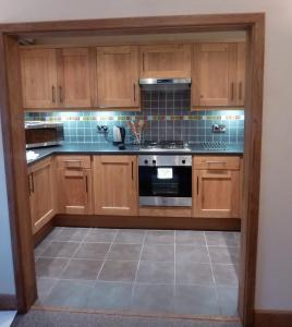 a kitchen with wooden cabinets and a stove at Hewlett Apartments in Cheltenham