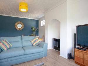 uma sala de estar com um sofá azul e uma televisão em Bethany em Brixham