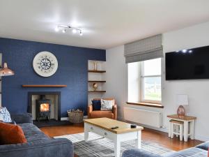 a living room with a couch and a fireplace at 1 Dalbuaick Farm Cottage in Carrbridge