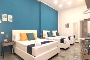 three beds in a room with a blue wall at TRACK 60 - PRIVATE ROOMS GARIBALDI in Naples