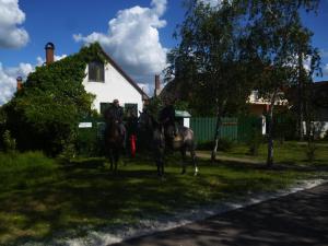 duas pessoas a andar a cavalo em frente a uma casa em Hajdu Lovasudvar Hortobágy em Hortobágy