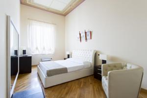 a white bedroom with a bed and a couch at Quattro canti luxury apartment in Palermo