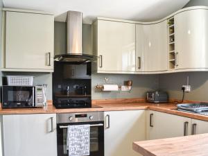een keuken met witte kasten en een fornuis met oven bij Hare Cottage in Westgate
