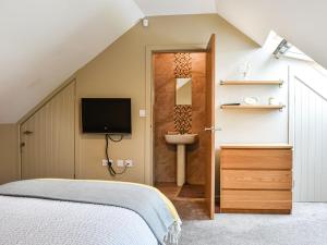 a bedroom with a bed and a bathroom with a sink at Hare Cottage in Westgate