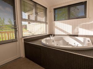 a bathroom with a tub and a large window at Lodge 6 - Inchyra in Perth