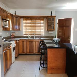 a kitchen with wooden cabinets and a island with bar stools at Comfortable & Secure Chateau in Kingston