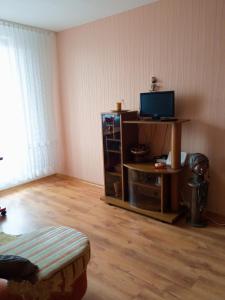 a living room with a tv and a wooden floor at BuTaS TaUrAgEje in Tauragė