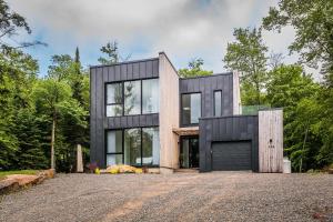 uma casa na floresta com uma fachada negra em Luxurious Heaven Lodge Tremblant-4 Bdrs W Hottub em Mont-Tremblant