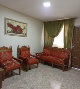 a living room with red chairs and a window at Casa a 5 minutos a pé da Basílica e da feira em Aparecida in Aparecida