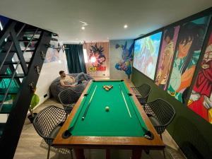 a man in a room with a pool table at Capsule Manga - Jacuzzi - Billard - Nintendo Switch - Netflix in Valenciennes