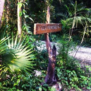 Una señal que dice Villa Ricochetneau en un tocón de árbol en Villa Morena Boutique Hotel Ecoliving, en Akumal