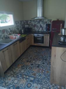 uma cozinha com piso em azulejo, um fogão e um lavatório. em sasu eco nature em Vendays-Montalivet