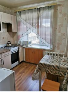une petite cuisine avec une table et une fenêtre dans l'établissement 1 комн апартаменты в центре рядом с парком, à Kostanay