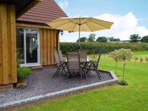 a patio with a table and chairs and an umbrella at Bumble Lodge in Llynclys