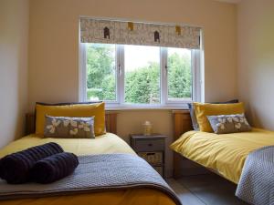 two beds in a room with two windows at Bumble Lodge in Llynclys