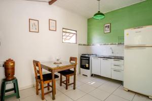 a kitchen with green walls and a table and a refrigerator at Casinha confortável próxima ao Centro in Paraty