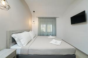 1 dormitorio con 1 cama blanca y TV en la pared en Villa Oresti en Panagia