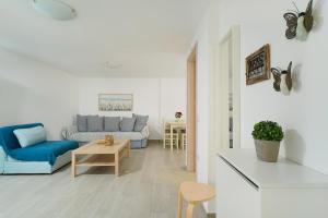 a white living room with a blue couch and a table at Villa Oresti in Panagia