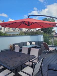 eine Terrasse mit Tischen, Stühlen und einem roten Regenschirm in der Unterkunft Central Modern Townhouse in Saundersfoot in Saundersfoot