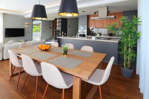 a dining room and kitchen with a wooden table and white chairs at OurMadeira - Bella Vita, tranquil in Calheta