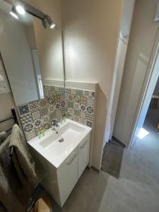 La salle de bains est pourvue d'un lavabo blanc et d'un miroir. dans l'établissement Studio bien équipé à 2 pas de la gare, à Béziers