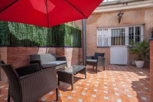 um pátio com um guarda-sol vermelho, cadeiras e uma mesa em GAVIDIA CENTER PREMIUM SUITES, FREE PARKING em Sevilha