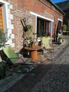 un patio con sillas, una mesa y un edificio de ladrillo en LOLA, en Montigny-sur-Crécy