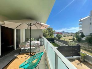 a balcony with an umbrella and a table and chairs at Appartement coquet in Marseille