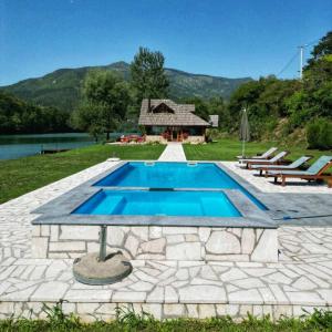 a swimming pool with a stone patio and a house at Villa California in Rezine