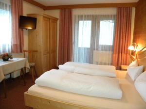 a hotel room with three beds and a table at Gästehaus Emberger in Mayrhofen