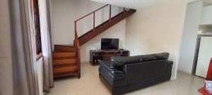ein Wohnzimmer mit einem schwarzen Ledersessel und einer Treppe in der Unterkunft Beach House uma casa no Caribe brasileiro in Arraial do Cabo