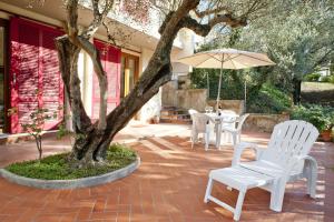 a patio with a tree and white chairs and an umbrella at B&B La Rocca in San Miniato